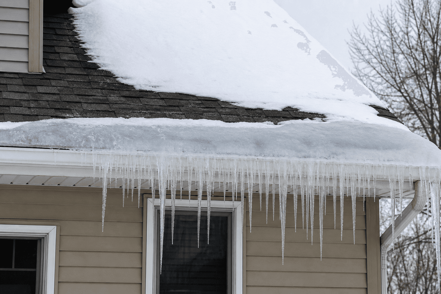 Winter eave on a Midwest house with a thick ice dam along the roof edge and icicles hanging from the gutter