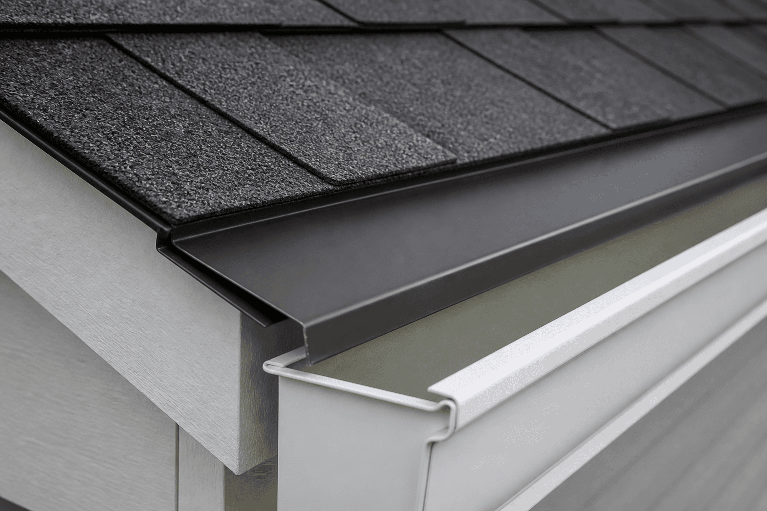 Bronze metal drip edge kicking into a white gutter under charcoal shingles